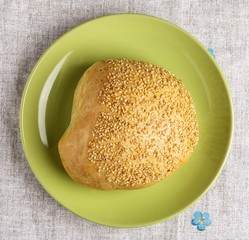 A sesame bun on a plate on a napkin.