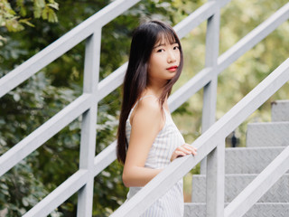 Outdoor portrait of beautiful young Chinese girl in dress suit top looking and smiling at you, happy girl with black long hair, beauty, emotion, expression and people lifestyle concept.