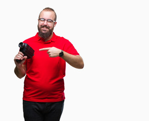 Young caucasian hipster man filmming using retro video camera over isolated background very happy pointing with hand and finger