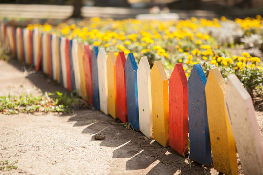 Multi-colored small fence around the flowerbed. Close-up