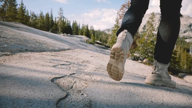 Close-up camera follows male legs in white desert shoes running and stopping on epic Yosemite forest rock slow motion.