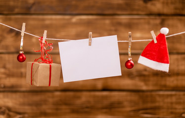 Nicholas hat, christmas balls, present and a note with copy space hang on a rope