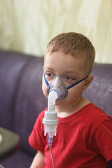 Caucasian boy inhales couples containing medication to stop coughing.