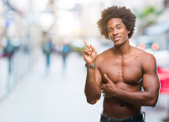 Fototapeta na wymiar Afro american shirtless man showing nude body over isolated background with a big smile on face, pointing with hand and finger to the side looking at the camera.