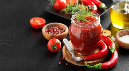 Gardinen Chilischoten Traditional  chili sauce in a glass jar with fresh herbs, tomatoes and olive oil.  © Nelea Reazanteva