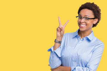 Young beautiful african american business woman over isolated background smiling with happy face winking at the camera doing victory sign. Number two.