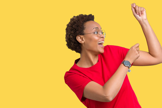 Beautiful young african american woman wearing glasses over isolated background Dancing happy and cheerful, smiling moving casual and confident listening to music