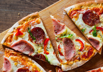 Pizza with Mozzarella cheese, ham, tomato sauce, salami, pepper, Spices and Fresh arugula. Italian pizza on wooden table background