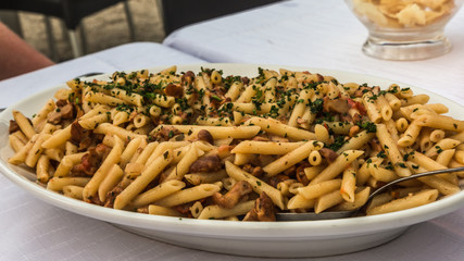 Al Funghi, mushroom pasta on a plate, sprinkled with parsley.