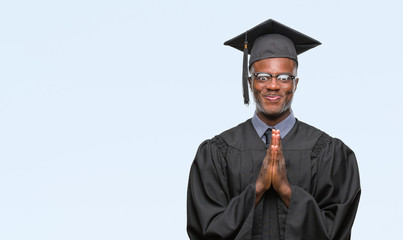 Young graduated african american man over isolated background praying with hands together asking...