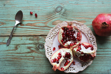 Pomegranates on white plate with spoon . Blue background . .