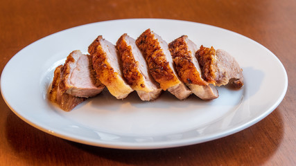Seared duck breast with crispy skin on a white ceramic plate 