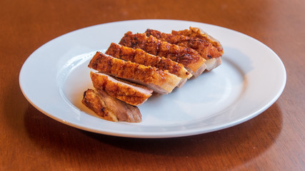 Seared duck breast with crispy skin on a white ceramic plate 