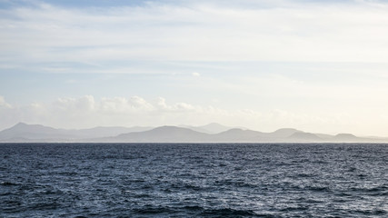 Fototapeta na wymiar Foggy mountain range on the horizon. The ocean in the foreground.
