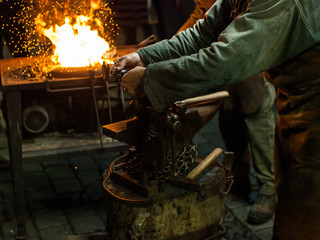 Fototapeta premium A blacksmith works with metal close to open fire. Christmas market in Prague, Czech Republic.