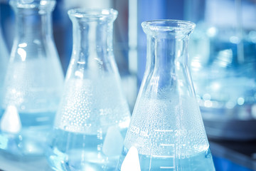 Glassware chemical test tube  with chemical solution that heat is steam in laboratory room, on blue tone color background, science research and testing concept, Close-up and selective focus