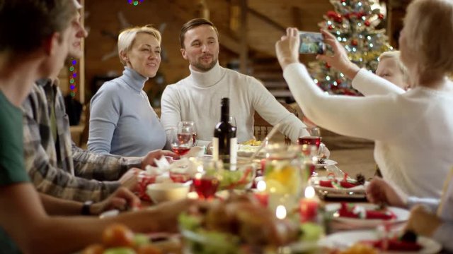 Grandmother takes a picture of husband and wife by Christmas table