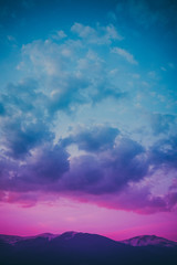 Photo depicting a beautiful moody frosty landscape. European alpine mountains with snow peaks on colorful evening sky background.