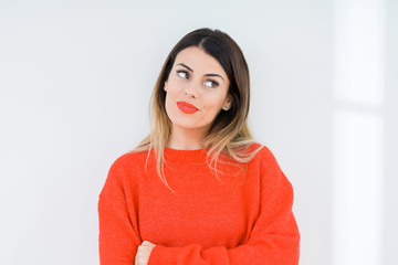 Young woman wearing casual red sweater over isolated background smiling looking side and staring away thinking.