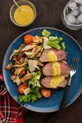 Salad with warm beef with oyster mushrooms, tomatoes and greens. Top view