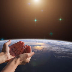 Woman's hands praying for Earth and nature. Elements of this image are furnished by NASA.