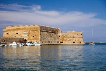 Fototapeta na wymiar Boats and motorboats under the walls of Koules Fortress in Heraklion.Fortress on the sea, tourist attraction of the city of Heraklion. Historic building in Crete, Greece.