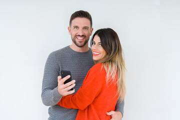 Beautiful young couple in love, kissing and hugging each other using smarthpone