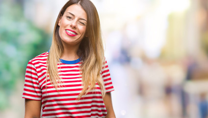 Young beautiful woman casual look over isolated background winking looking at the camera with sexy expression, cheerful and happy face.