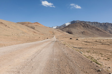 Fototapeta na wymiar Desert landscape in the area of Ak-Baital Pass with road in the Pamir Mountains in Tajikistan