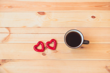 Mug of coffee and two red hearts on wooden background. Top view with copy space.