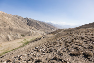 Pamir Highway in the desert landscape of the Pamir Mountains in Tajikistan. Afghanistan is on the left