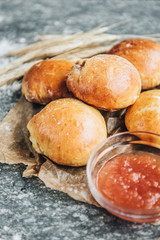 Fresh baked yeast buns filled with apple jam on gray background with flour.