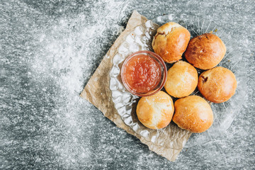Obraz premium Fresh baked yeast buns filled with apple jam on gray background with flour.