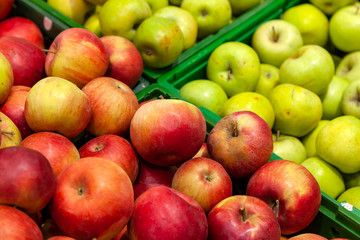 Close-up large, selective, colorful green and red apples on the counter call for a healthy lifestyle. New ripe crop in supermarket in assortment.