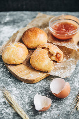Fresh baked yeast buns filled with apple jam on gray background with flour.