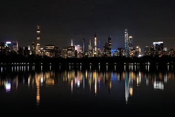 Naklejka premium Lights of the Manhattan Skyline Reflecting in a Lake in Central Park. New York, USA