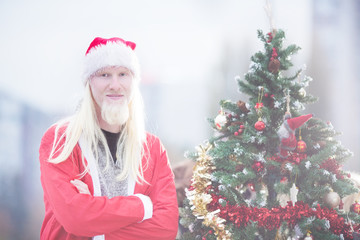Young man as Santa with Christmas tree outdoors