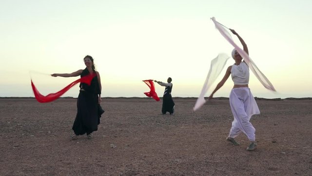 Absurd show with ribbons at seaside at sunset shaky footage