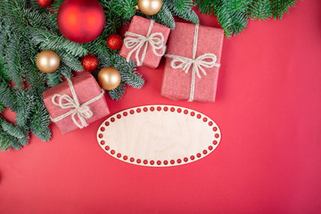 Christmas composition. Christmas red decorations, fir tree branches with toys gift boxes on red background. Flat lay, top view, copy space