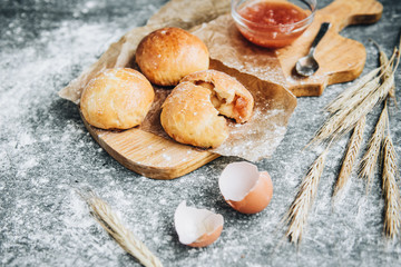 Fresh baked yeast buns filled with apple jam on gray background with flour.