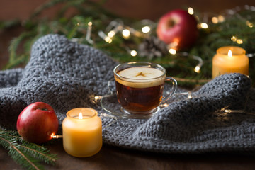 Obraz na płótnie Canvas Hot mulled apple cider on woolen scarf and candle, wooden background