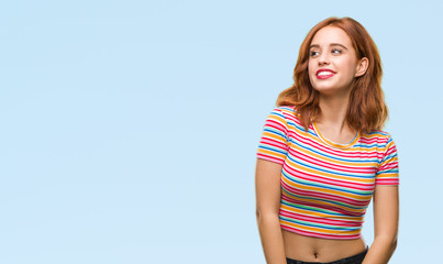 Young beautiful woman over isolated background looking away to side with smile on face, natural expression. Laughing confident.