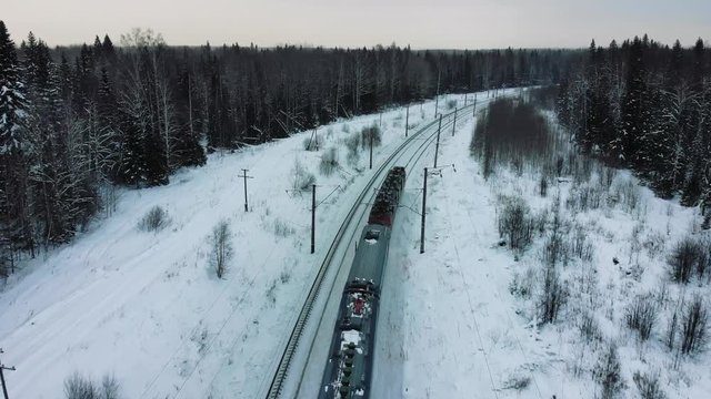 Aerial view of railroad through winter forest with snow covered trees in Switzerland