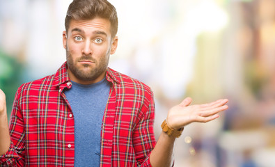 Young handsome man over isolated background clueless and confused expression with arms and hands raised. Doubt concept.