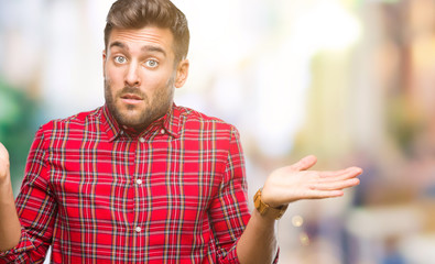 Young handsome man over isolated background clueless and confused expression with arms and hands raised. Doubt concept.