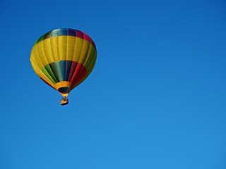 Brightly coloured hot air balloon in a clear blue sky with copy space