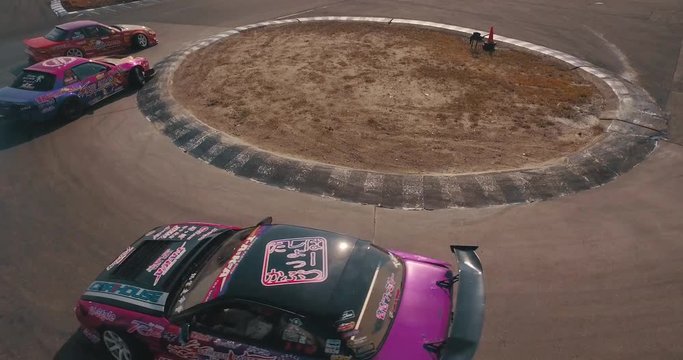 Close Up Stabilized Tracking Shot of Multiple Race Cars Drifting Around a Circle Curve.