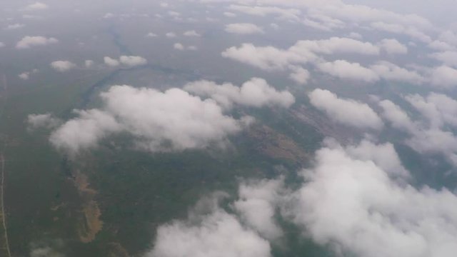 Aerial view flying through cloud scattered sky above the Kenyan landscape below