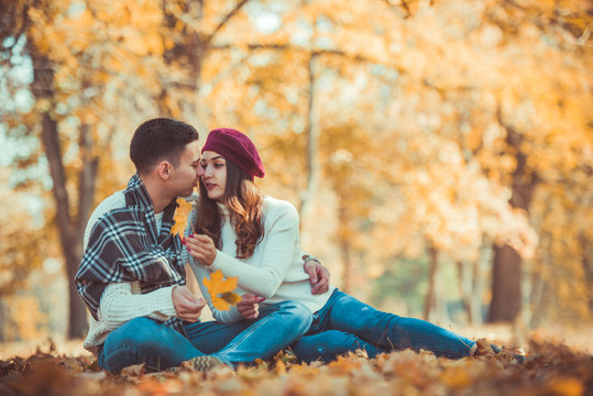 Stylish couple trying to kiss in the park