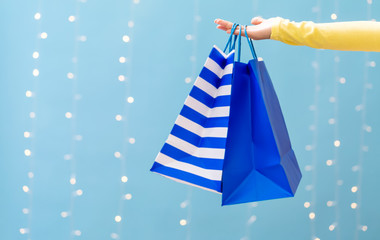 Woman holding shopping bags on a shiny light blue background